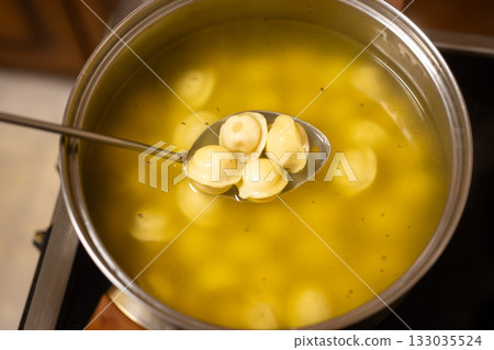 Spoon with Boiled Dumplings Over Pot of Broth Spoon with Boiled Dumplings Over Pot of Broth 133035524