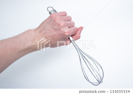 Hand Holding Metal Whisk on Light Background 133035554