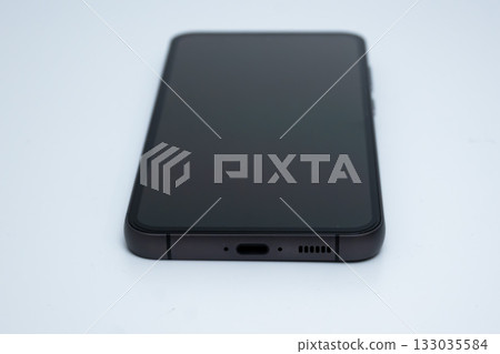 Newest smartphone with black screen lies on white surface in studio lighting 133035584