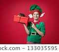Merry Christmas concept. Smiling funny boy in Santa's elf costume holding 133035595