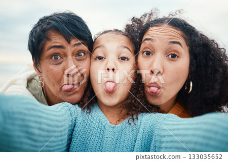 Funny, tongue out and portrait of a family selfie, silly and goofy at the beach in Bali. Comic, crazy and girl taking a photo with a mother and grandmother for a playful memory on holiday at the sea 133035652