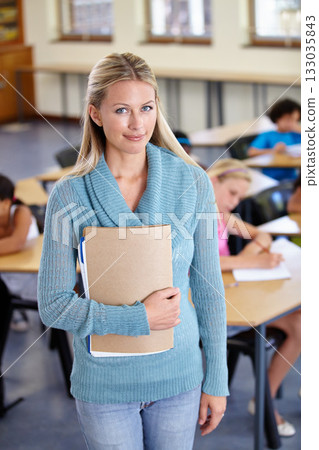 Teacher, portrait and woman with binder in class, elementary school or classroom. Education, teaching and female educator with folder, paperwork or documents for serious learning, knowledge or study. 133035843