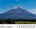 The majestic and symbolic Mount Fuji, capped with snow and towering silently against the deep blue sky. 133035914