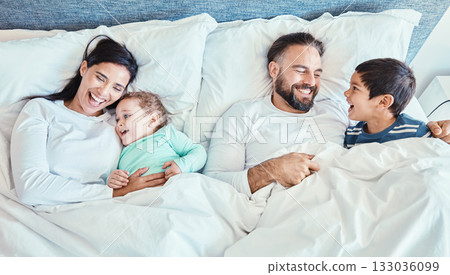 Waking up, bed and family relax, happy and bond while resting, talking and laughing from above at home. Bedroom, fun and kids with parents in the morning, playful and caring while lying and embracing 133036099