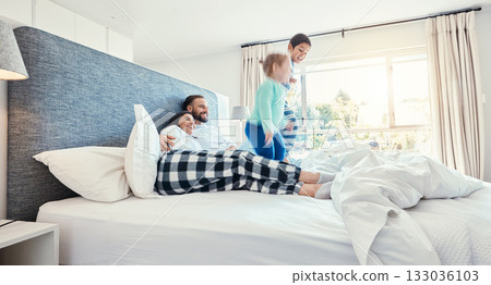Love, family and playing in bedroom, quality time and happiness in the morning, vacation and cheerful. Mother, father and children on bed, jumping and joyful with smile, bonding and loving together 133036103