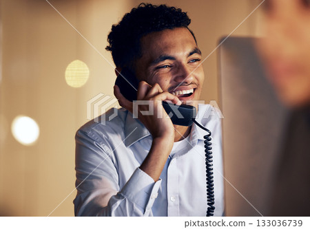 Telephone, night and businessman on a phone call in the office talking while working on a computer. Discussion, communication and professional male employee speaking on a landline in the workplace. Telephone, night and businessman on a phone call in the office talking while working on a computer. Discussion, communication and professional male employee speaking on a landline in the workplace. 133036739