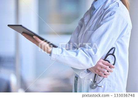 Digital tablet, healthcare and doctor in the hospital analyzing test results or doing research. Technology, stethoscope and professional female medical worker reading information on a mobile device. 133036748