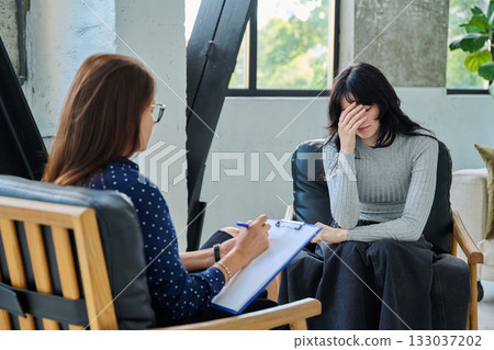 Sad stressed young woman patient talking with female psychologist, mental counselor Sad stressed young woman patient talking with female psychologist, mental counselor 133037202