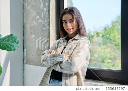 Portrait of confident successful teenage girl posing with crossed arms near window Portrait of confident successful teenage girl posing with crossed arms near window 133037297