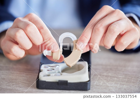 Hearing aid, disability help tool and hands with hospital, wellness and medical audio innovation. Listening, audio and deaf device for healthcare, disabled people and implant for language hear 133037554