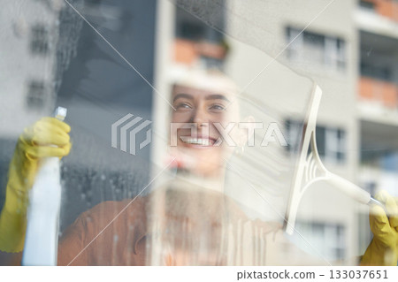 Window cleaning, smile and happy woman at home washing windows with glass cleaner. Helping, working and maid with spray detergent product for house chores and disinfectant wipe with sanitation soap 133037651