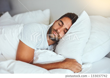 Man, sleeping and bed in morning rest for healthy wellness, peace and quiet on comfort pillow at home. Tired or exhausted male person asleep or dreaming on peaceful holiday or weekend in the bedroom 133037742