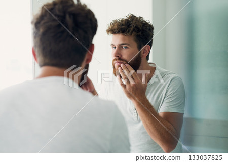 Skincare, beauty and beard with a man in the bathroom of his home in the morning for fresh hygiene. Mirror, reflection and self care with a handsome young male person checking his face or skin Skincare, beauty and beard with a man in the bathroom of his home in the morning for fresh hygiene. Mirror, reflection and self care with a handsome young male person checking his face or skin 133037825