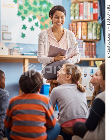 Teacher, reading book and school kids in a classroom for learning, education or story time. Happy woman teaching children or students about happiness, language and literature or development at school 133037893
