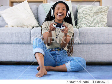 Black woman, gaming and smile with controller by living room sofa for fun match or online game at home. Happy African American female playing video games with headphones for entertainment or esports Black woman, gaming and smile with controller by living room sofa for fun match or online game at home. Happy African American female playing video games with headphones for entertainment or esports 133038700