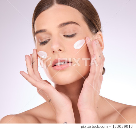 Beauty, skincare or girl with face cream product in daily grooming treatment with makeup cosmetics in studio. Dermatology, mockup space background or female model applying facial sunscreen lotion Beauty, skincare or girl with face cream product in daily grooming treatment with makeup cosmetics in studio. Dermatology, mockup space background or female model applying facial sunscreen lotion 133039013