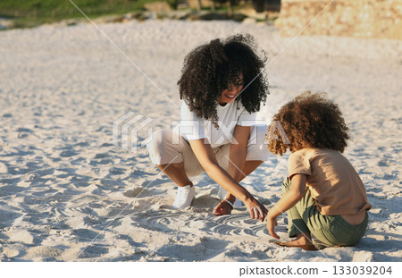 Black family at the beach, mother and child play in sand on summer holiday, freedom and travel with nature outdoor. Fun together, vacation and carefree with happiness, woman and girl in Jamaica Black family at the beach, mother and child play in sand on summer holiday, freedom and travel with nature outdoor. Fun together, vacation and carefree with happiness, woman and girl in Jamaica 133039204