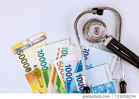 Stethoscope placed on various South Korean won banknotes indicating healthcare funding in an economic context 133039234
