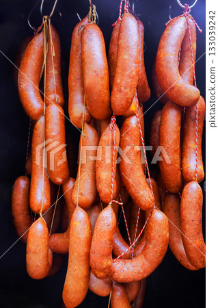 Handcrafted sausages hang in market display, showcasing local meat preparation skills traditions Handcrafted sausages hang in market display, showcasing local meat preparation skills traditions 133039242