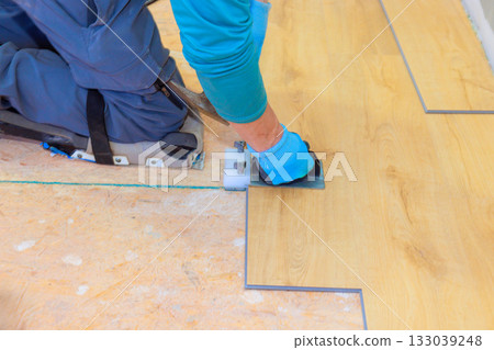 Professional worker installing laminate flooring in residential space during home renovation project Professional worker installing laminate flooring in residential space during home renovation project 133039248