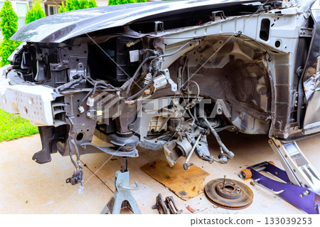 Car undergoing extensive repair work in driveway hours with tools parts scattered nearby 133039253