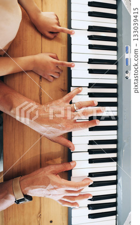 Piano, top view and hands of kid learning with father in home, playing or bonding together. Development, education or parent teaching child how to play music instrument, acoustic or electric keyboard 133039415