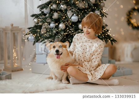 Child and Dog Sitting by Christmas Tree Smiling Child and Dog Sitting by Christmas Tree Smiling 133039915