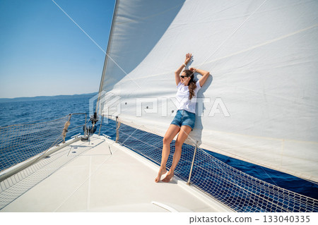 Young woman standing on the bow of a sailing yacht during a sea journey. Freedom, wind, and mindful solitude in maritime travel Young woman standing on the bow of a sailing yacht during a sea journey. Freedom, wind, and mindful solitude in maritime travel 133040335