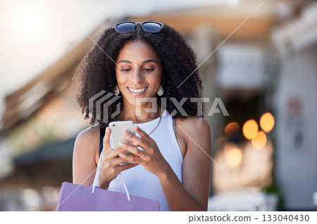 Black woman, phone reading and shopping bag of a customer on a online shop app for discount. Retail store promotion, urban and mobile networking of a female on a city street with blurred background 133040430