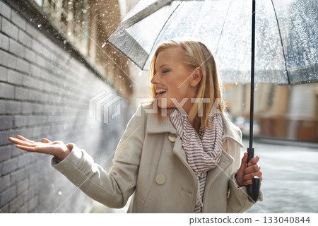 Smile, happy woman and rain feel in the city with umbrella, freedom and happiness on holiday. Winter weather, raining and urban street with a young female person on a sidewalk and vacation outdoor Smile, happy woman and rain feel in the city with umbrella, freedom and happiness on holiday. Winter weather, raining and urban street with a young female person on a sidewalk and vacation outdoor 133040844