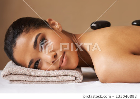 Portrait of woman, rock or back massage in spa to relax for zen, resting or wellness physical therapy. Face of girl client in salon to exfoliate for skincare healing treatment or hot stone therapy 133040898
