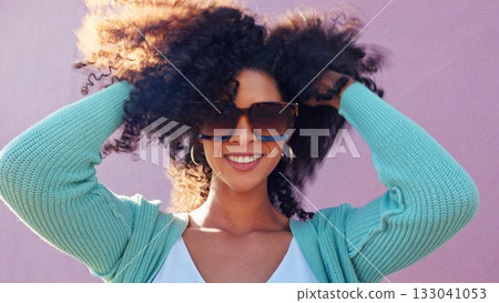 Black woman, hair shake and happy with smile on pink background by wall with freedom. Fashion, style and trendy sunglasses with outfit of female person with afro hairstyle outdoor haircare and wind 133041053