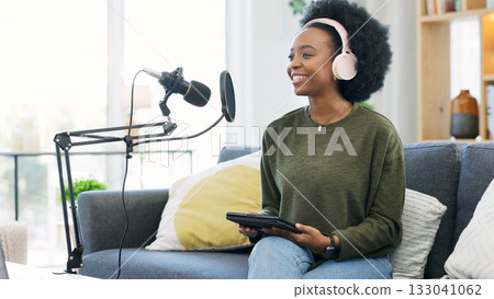 Headphones, tablet and black woman on microphone in podcast at home in living room of influencer. Technology, smile and content creator on mic for live broadcast, recording audio and radio on sofa Headphones, tablet and black woman on microphone in podcast at home in living room of influencer. Technology, smile and content creator on mic for live broadcast, recording audio and radio on sofa 133041062