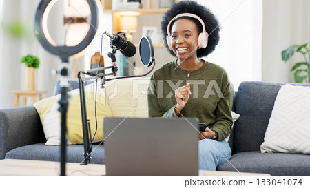 Headphones, laptop and black woman on microphone in podcast at home in living room of influencer. Technology, smile and content creator on mic for broadcast, communication and radio talk show on sofa Headphones, laptop and black woman on microphone in podcast at home in living room of influencer. Technology, smile and content creator on mic for broadcast, communication and radio talk show on sofa 133041074