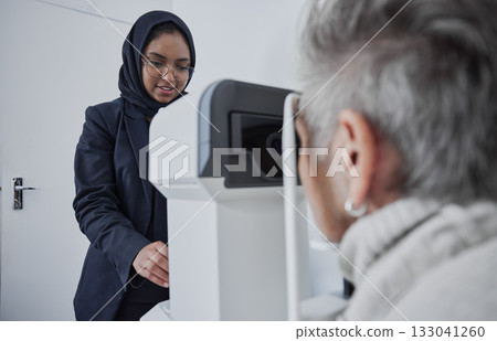 Optometrist, muslim woman and testing eyesight health in optometry lab with optical machine indoors. Senior patient in eye clinic, person at appointment to scan diagnosis and ophthalmologist working 133041260