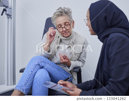 Optometry, healthcare and woman filling in a form before doing a eye test in a optic clinic. Health insurance, ophthalmology and optician helping senior female patient with document in optical store. 133041262