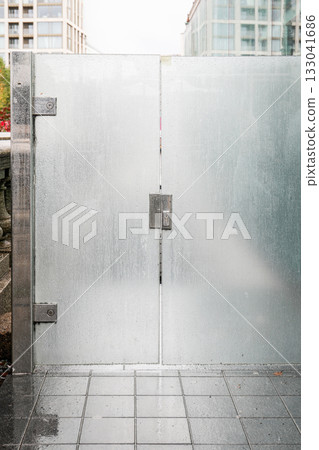 Modern frosted glass gate with raindrops and metal frame in urban city environment 133041686