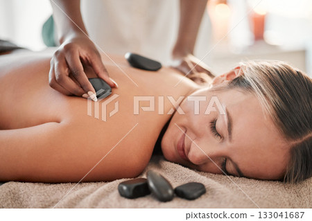 Woman, hot stone massage and masseuse, hand and zen with holistic therapy and spa treatment for back. Calm, peace of mind and face, healing and stress relief with self care at wellness resort Woman, hot stone massage and masseuse, hand and zen with holistic therapy and spa treatment for back. Calm, peace of mind and face, healing and stress relief with self care at wellness resort 133041687