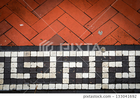 Red brick pavement with geometric black and white mosaic tile border, showing architectural pattern Red brick pavement with geometric black and white mosaic tile border, showing architectural pattern 133041692