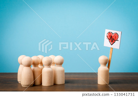 Wooden figures symbolizing healthcare support and medical care concept with one holding a red heart Wooden figures symbolizing healthcare support and medical care concept with one holding a red heart 133041731
