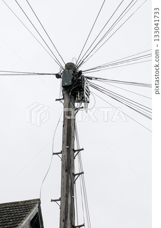 Wooden telephone pole with multiple communication cables and wires against cloudy sky Wooden telephone pole with multiple communication cables and wires against cloudy sky 133041733
