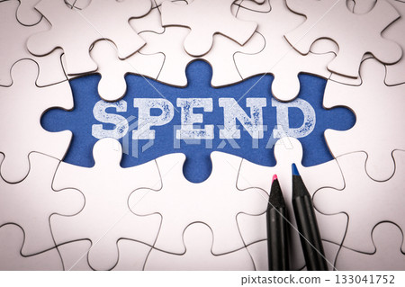 Word spend written on blue background under white puzzle pieces Word spend written on blue background under white puzzle pieces 133041752