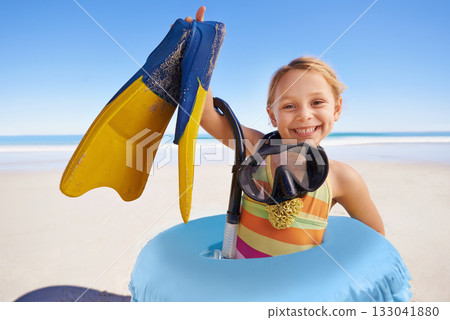 Beach, portrait and girl child with flippers, snorkel and inflatable swimming ring on ocean background. Face, happy and kid swimmer smiling, excited and ready for adventure while traveling in Miami 133041880