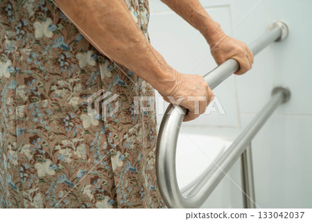Asian elderly woman patient use handrail safety in toilet support rail in bathroom. 133042037