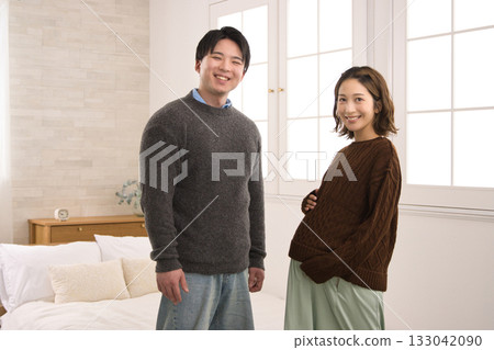 A young couple standing by the window, a pregnant woman A young couple standing by the window, a pregnant woman 133042090