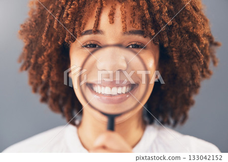 Happy, portrait and black woman with magnifying glass in a studio for a investigation or research. Happiness, smile and portrait of a young African female model with a zoom lens by a gray background. Happy, portrait and black woman with magnifying glass in a studio for a investigation or research. Happiness, smile and portrait of a young African female model with a zoom lens by a gray background. 133042152