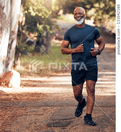 Music earphones, running and black man in nature for health, wellness and fitness. Radio, podcast and smile of happy senior athlete training, exercise and workout, cardio and jog outdoors at park. 133042166