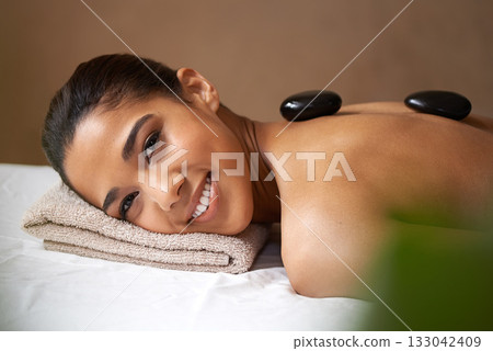Portrait of happy girl, rock or back massage in spa to relax for zen, resting or wellness physical therapy. Face of woman smiling in salon to exfoliate for body healing treatment or hot stone therapy Portrait of happy girl, rock or back massage in spa to relax for zen, resting or wellness physical therapy. Face of woman smiling in salon to exfoliate for body healing treatment or hot stone therapy 133042409