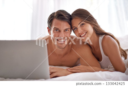 Laptop, love and portrait of a couple in bed together while watching a online movie or video at their home. Happiness, smile and woman browsing the internet on computer with her husband in bedroom. Laptop, love and portrait of a couple in bed together while watching a online movie or video at their home. Happiness, smile and woman browsing the internet on computer with her husband in bedroom. 133042425