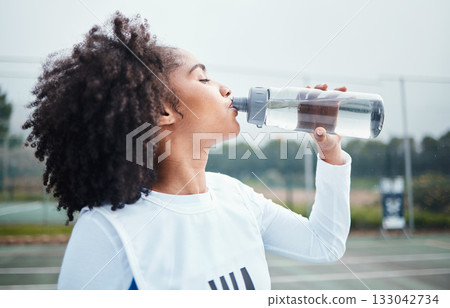 Sports, black woman and drinking water at court during training, workout and sport exercise outdoors. Fitness, thirsty and girl with bottle for wellness, hydration and recovery during practice Sports, black woman and drinking water at court during training, workout and sport exercise outdoors. Fitness, thirsty and girl with bottle for wellness, hydration and recovery during practice 133042734